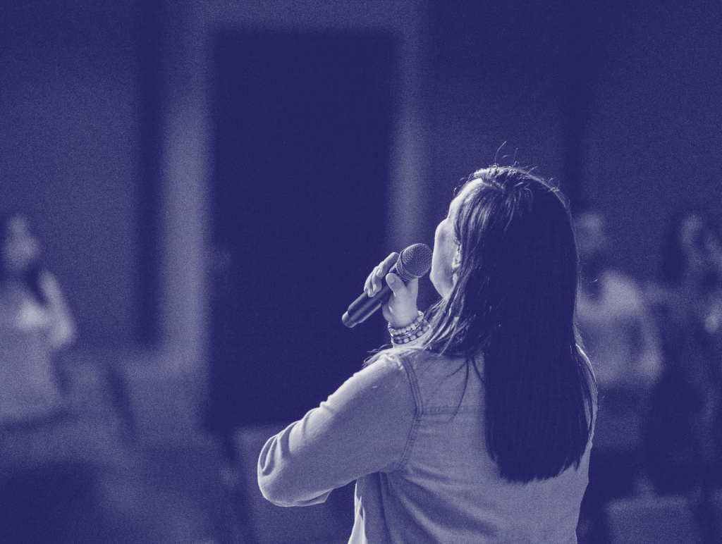 Woman from the back holding a microphone, speaking to an audience